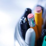 A jar filled with pencils, pens and other writing tools